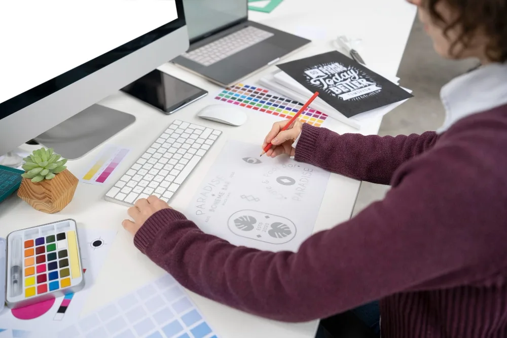Entrepreneur indépendant travaillant sur une charte de marque, avec ordinateur, carnet de notes et palette de couleurs sur un bureau