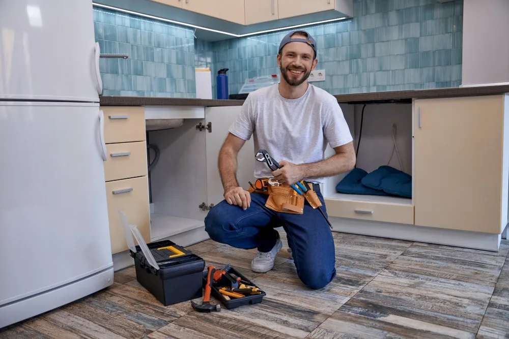 Un bricoleur équipé d’une caisse à outils intervient chez un particulier dans un salon lumineux