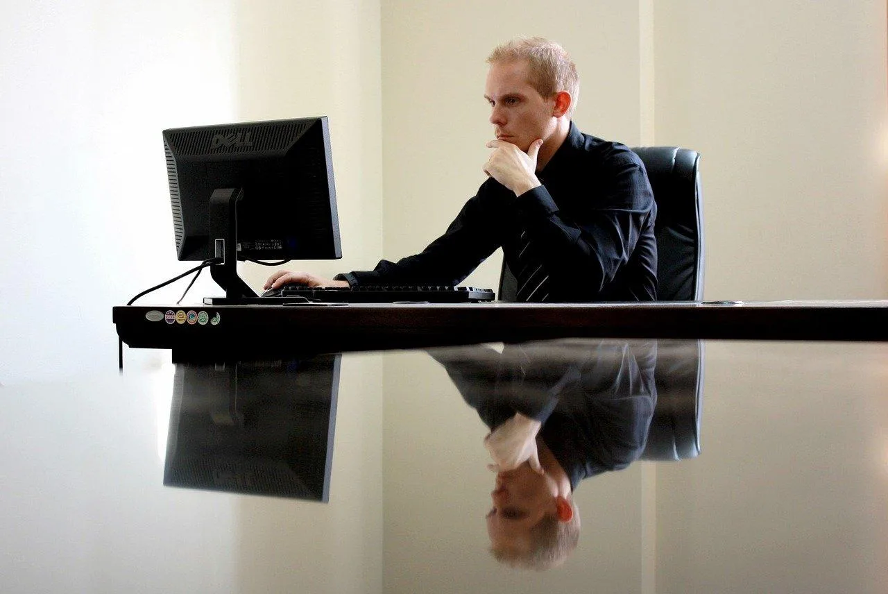 Photo d’un entrepreneur consultant un dossier administratif et un ordinateur pour créer son entreprise individuelle.