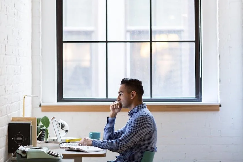 Entrepreneur individuel consultant ses documents de protection sociale sur un bureau avec ordinateur, calculatrice et relevé de cotisations