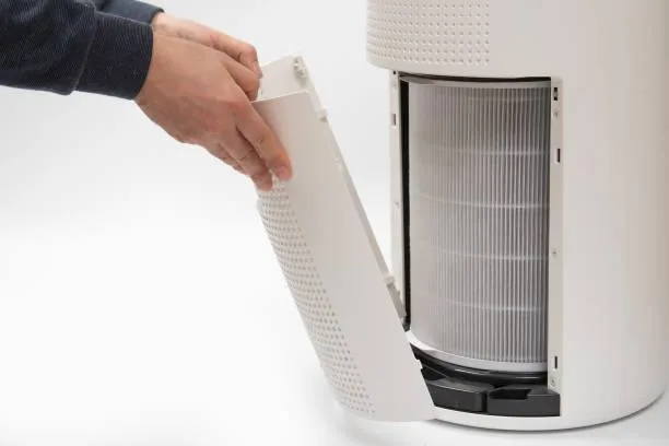 Purificateur d’air posé dans un bureau moderne avec ordinateur, plante verte et lumière naturelle