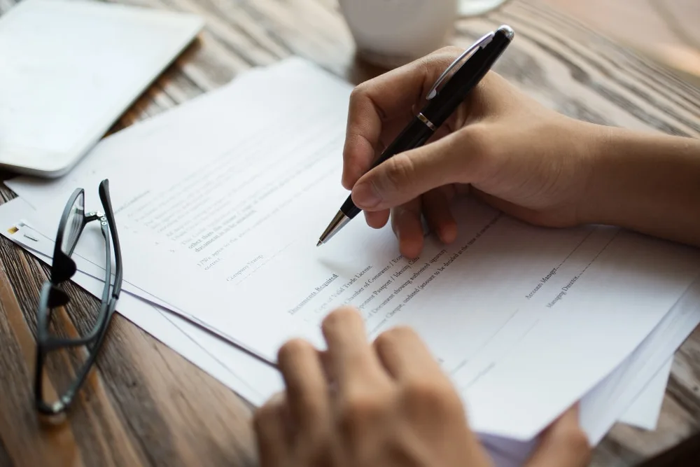 Un entrepreneur individuel compare des contrats d’assurance professionnelle sur son ordinateur, avec des documents de travail à côté.