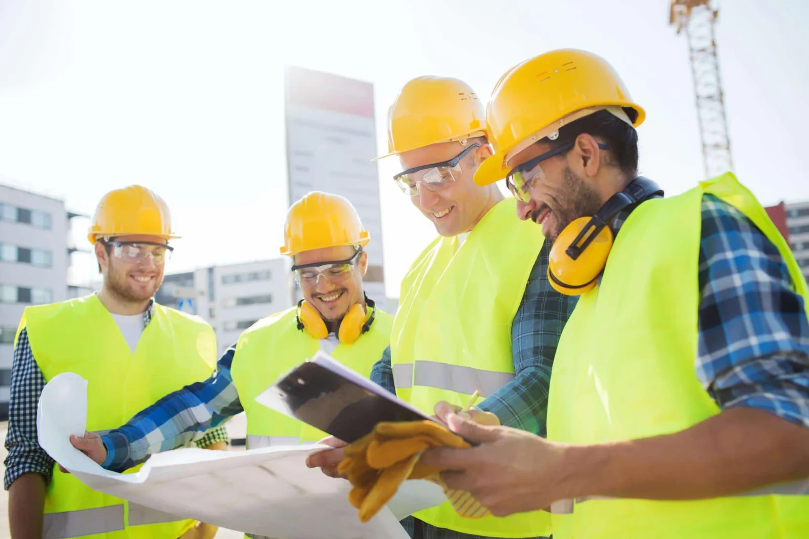 Un salarié en gilet haute visibilité orange sur un chantier routier extérieur, près de véhicules et d’engins de travaux.