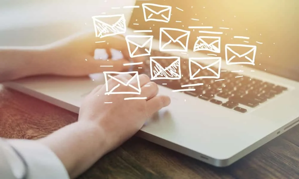 Un entrepreneur indépendant rédige une campagne d’emailing sur ordinateur portable, avec tableau de bord marketing à l’écran.