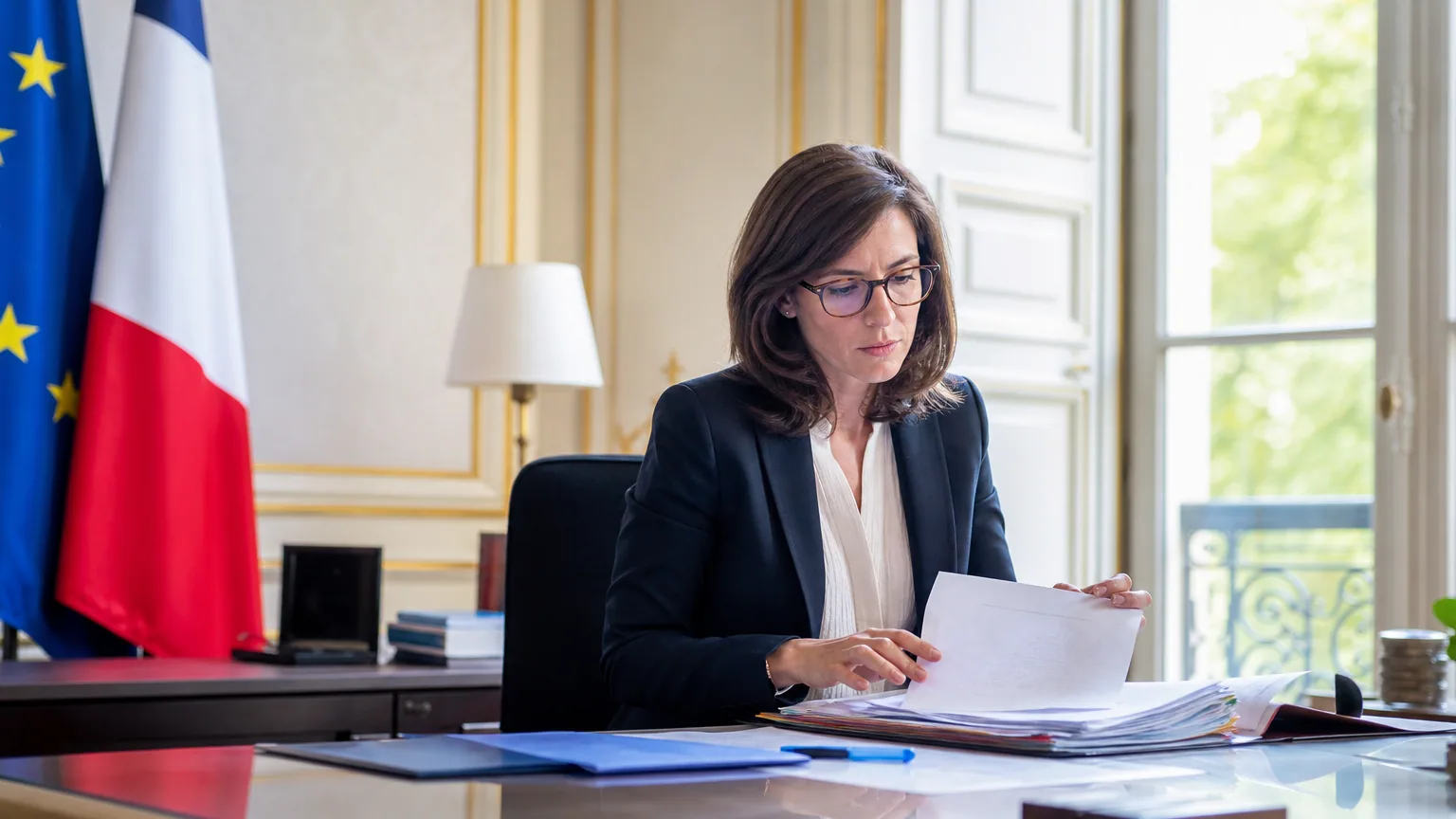 Agent de la fonction publique en tenue professionnelle consultant un document administratif dans un bureau lumineux