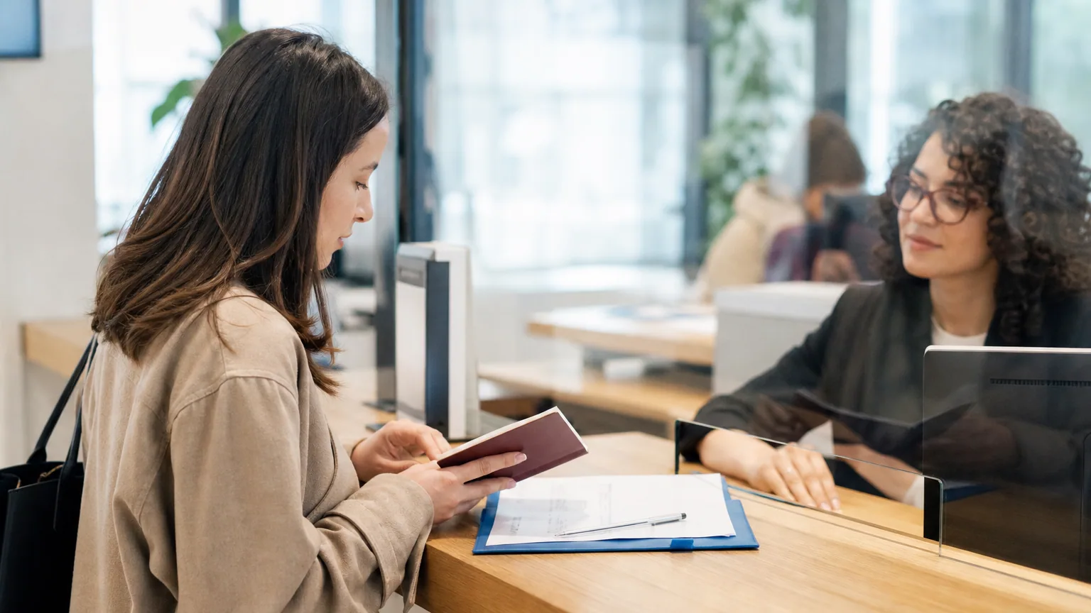 Personne consultant des documents administratifs et un passeport à un bureau, stylo à la main