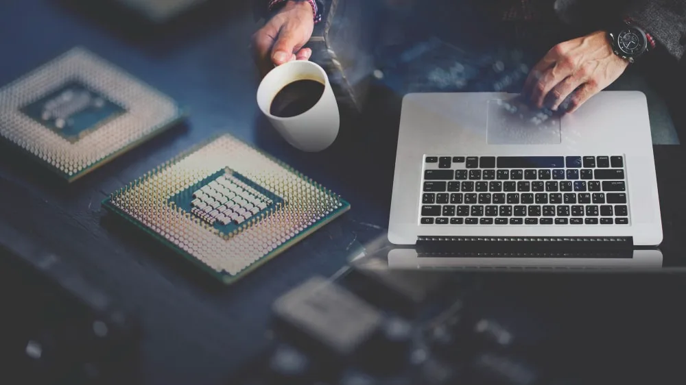Un entrepreneur indépendant échange avec un technicien informatique devant un ordinateur portable dans un petit bureau
