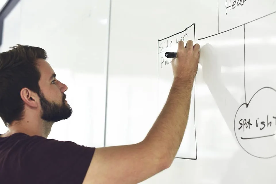 Une entrepreneuse prépare un planning d’événement sur ordinateur, avec devis, carnet de notes et échantillons de décoration sur la table.